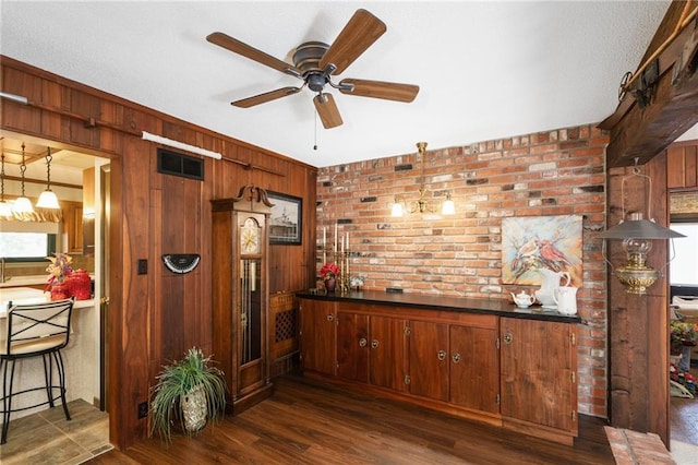 bar area featuring wood walls, a ceiling fan, brick wall, and dark wood finished floors