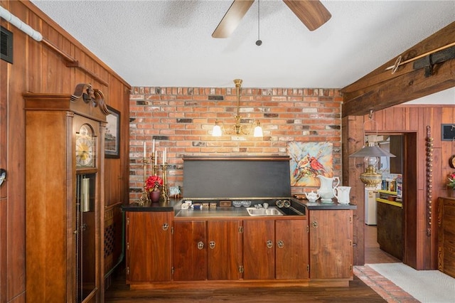 bar featuring wooden walls, ceiling fan, dark wood-style flooring, and a textured ceiling