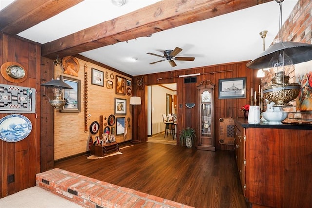 foyer featuring wood walls, beam ceiling, wood finished floors, and a ceiling fan