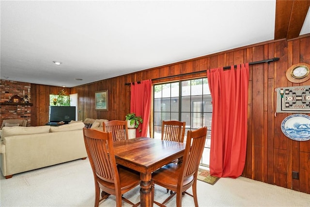 carpeted dining area featuring wood walls