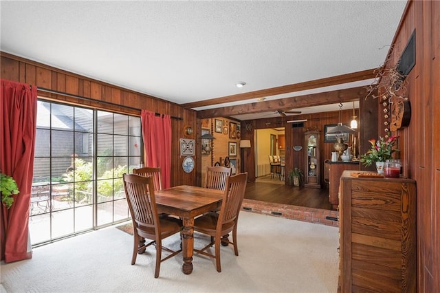 carpeted dining space with wooden walls