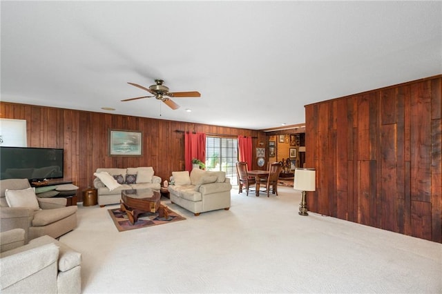 carpeted living room with wooden walls and a ceiling fan