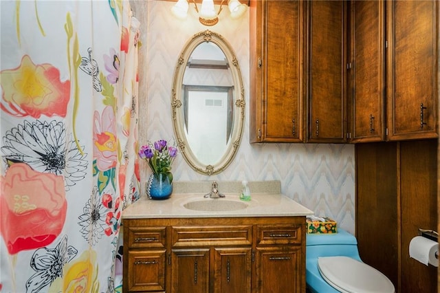 bathroom with wallpapered walls, vanity, and toilet
