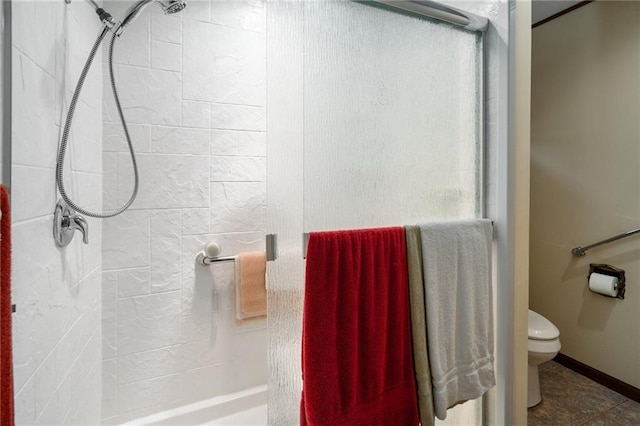 bathroom featuring a shower stall, toilet, and baseboards