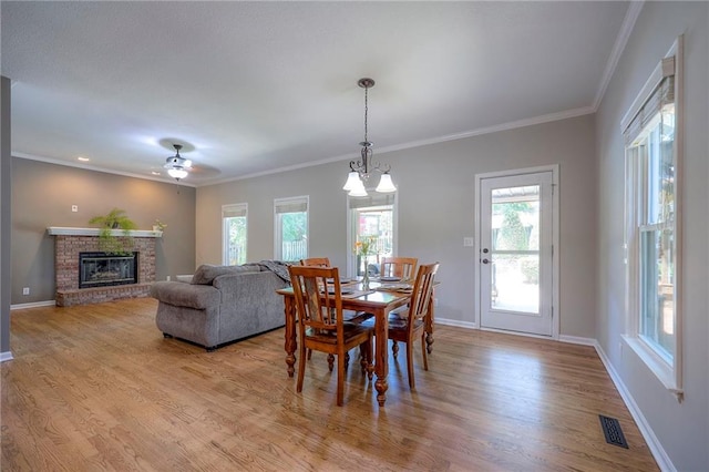 1906 Blackbird Cir, Kearney, MO 64060 - dining area with wood finished floors, plenty of natural light, a brick fireplace, ornamental molding, and ceiling fan