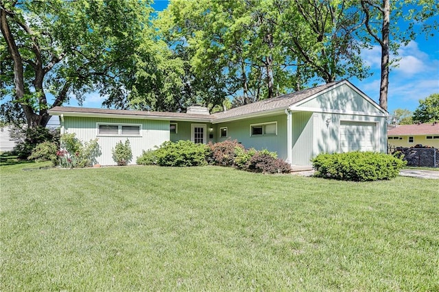 single story home featuring an attached garage, a front yard, and a chimney