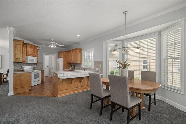 14393 S Cody St, Olathe, KS 66062 - dining space featuring crown molding, a ceiling fan, dark colored carpet, and baseboards