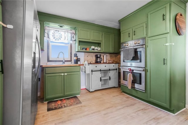 1332 Clark Rd, Williamsburg, KS 66095 - kitchen with stainless steel appliances, green cabinets, a sink, backsplash, and light wood-style floors