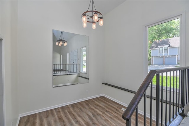 3512 Apple Tree Ln, Gladstone, MO 64119 - stairs featuring a chandelier, healthy amount of natural light, wood finished floors, and baseboards