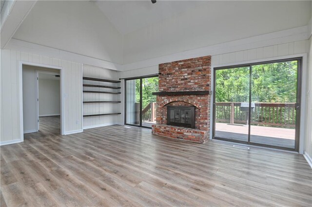 3512 Apple Tree Ln, Gladstone, MO 64119 - unfurnished living room with wood finished floors, high vaulted ceiling, baseboards, and a brick fireplace