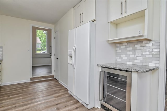 3512 Apple Tree Ln, Gladstone, MO 64119 - kitchen with wine cooler, white fridge with ice dispenser, light wood finished floors, backsplash, and light stone counters