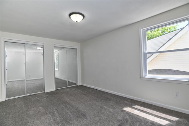 3512 Apple Tree Ln, Gladstone, MO 64119 - unfurnished bedroom featuring two closets, dark carpet, and baseboards