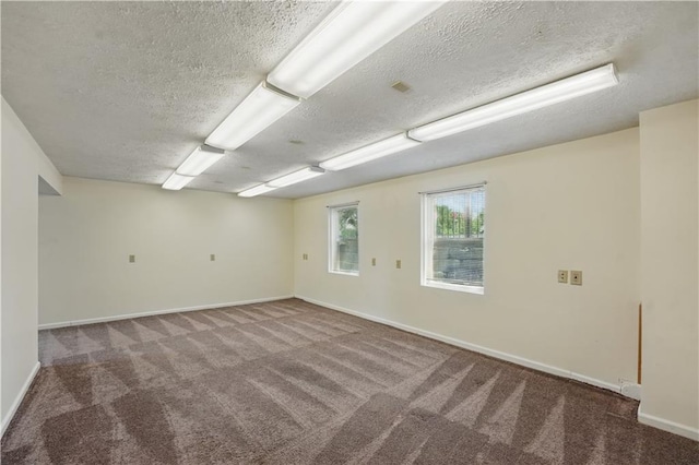 empty room featuring carpet, a textured ceiling, and baseboards