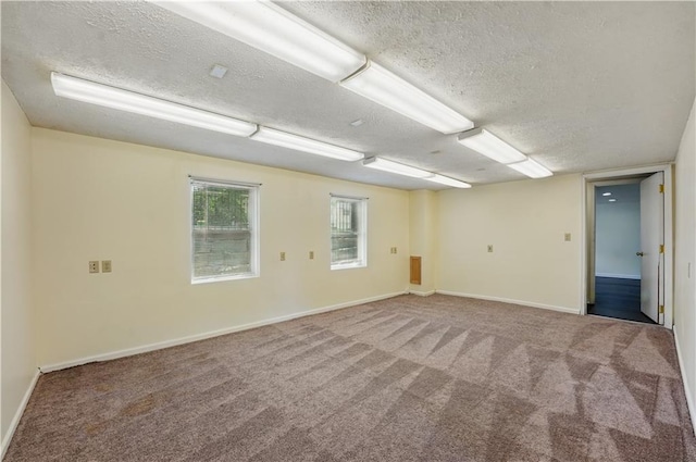 carpeted empty room featuring a textured ceiling and baseboards