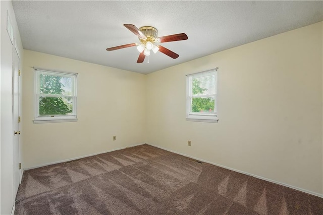 carpeted spare room with plenty of natural light, ceiling fan, and baseboards