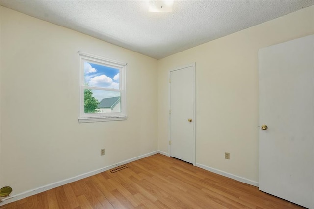 unfurnished bedroom featuring light wood-style floors, baseboards, and a textured ceiling