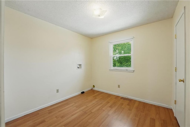 unfurnished room with light wood-style flooring, baseboards, and a textured ceiling
