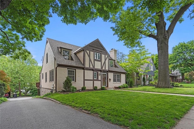 6843 Locust St, Kansas City, MO 64131 - tudor house with a chimney, a front yard, a shingled roof, stucco siding, and brick siding