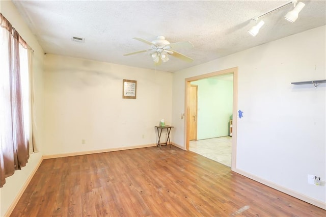 1175 SW State Route 58th Hwy, Holden, MO 64040 - empty room with wood finished floors, ceiling fan, a textured ceiling, baseboards, and track lighting