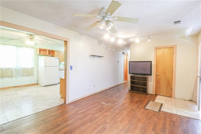 1175 SW State Route 58th Hwy, Holden, MO 64040 - unfurnished living room featuring a ceiling fan, a textured ceiling, light wood finished floors, rail lighting, and baseboards