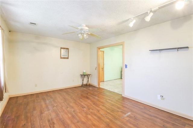 1175 SW State Route 58th Hwy, Holden, MO 64040 - spare room featuring wood finished floors, a ceiling fan, track lighting, a textured ceiling, and baseboards
