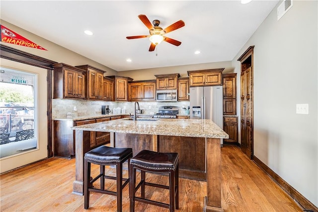 4000 S Buckner Tarsney Rd, Grain Valley, MO 64029 - kitchen with appliances with stainless steel finishes, a sink, wood finished floors, a ceiling fan, and an island with sink