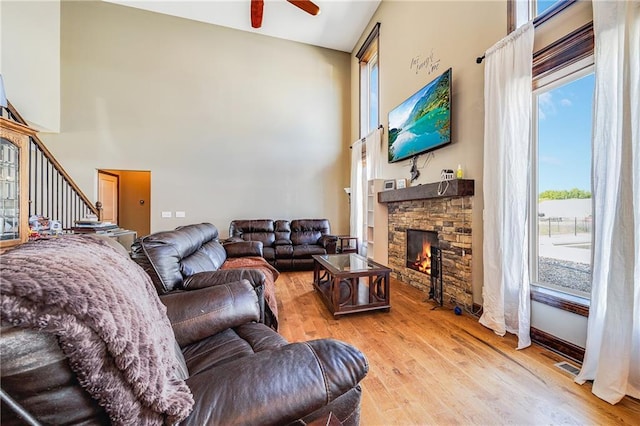 4000 S Buckner Tarsney Rd, Grain Valley, MO 64029 - living area featuring a towering ceiling, a ceiling fan, healthy amount of natural light, a stone fireplace, and light wood finished floors