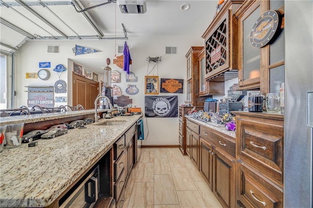 4000 S Buckner Tarsney Rd, Grain Valley, MO 64029 - kitchen featuring a sink, light stone countertops, freestanding refrigerator, glass insert cabinets, and brown cabinets