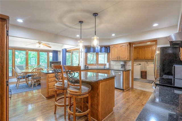 1407 SW Meyer Blvd, Blue Springs, MO 64015 - kitchen featuring stainless steel appliances, washing machine and dryer, a sink, light wood-style flooring, and ceiling fan