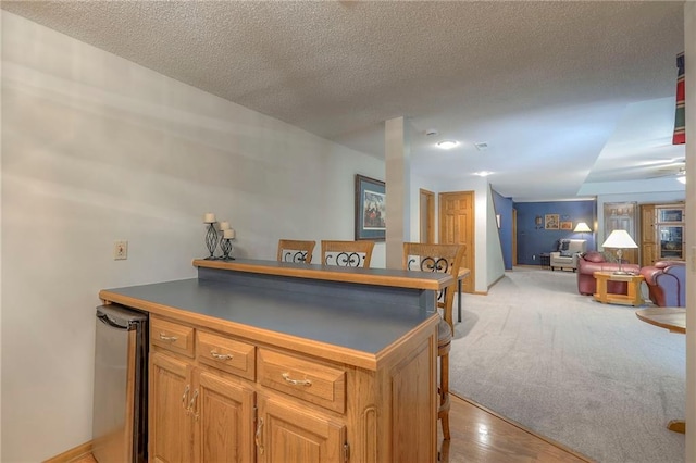 1407 SW Meyer Blvd, Blue Springs, MO 64015 - kitchen featuring dark countertops, a breakfast bar area, open floor plan, a textured ceiling, and brown cabinetry