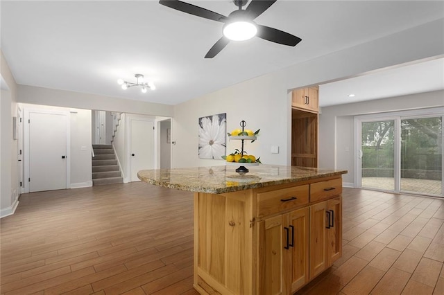 10234 Monrovia St, Lenexa, KS 66215 - kitchen featuring wood finished floors, light stone counters, a ceiling fan, and a center island