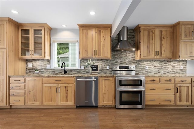 10234 Monrovia St, Lenexa, KS 66215 - kitchen with appliances with stainless steel finishes, wall chimney range hood, a sink, light brown cabinetry, and recessed lighting