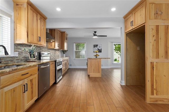 10234 Monrovia St, Lenexa, KS 66215 - kitchen with appliances with stainless steel finishes, a sink, under cabinet range hood, baseboards, and tasteful backsplash