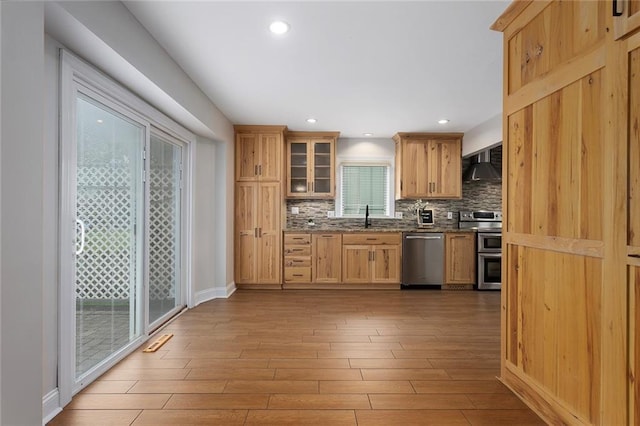 10234 Monrovia St, Lenexa, KS 66215 - kitchen featuring appliances with stainless steel finishes, wall chimney exhaust hood, backsplash, light wood-style floors, and a sink