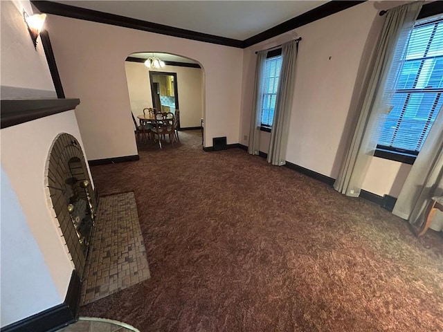 unfurnished living room with carpet floors, arched walkways, crown molding, and baseboards