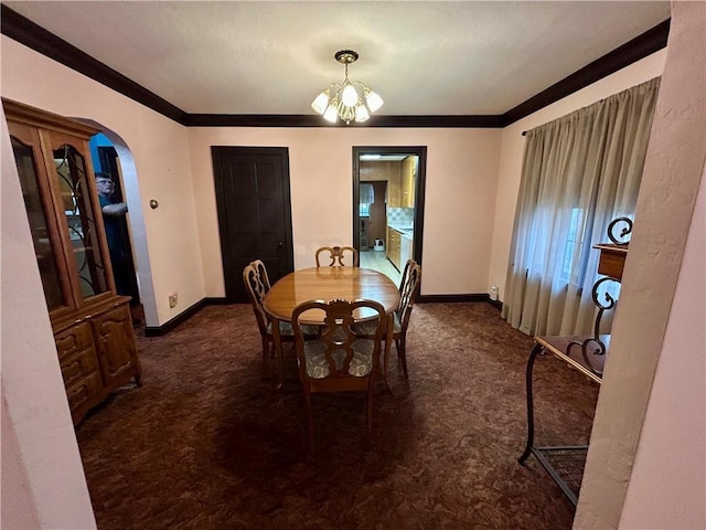 dining room featuring carpet, baseboards, ornamental molding, and a chandelier