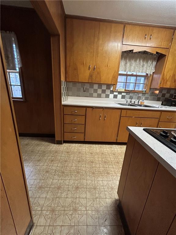kitchen with a sink, brown cabinets, tasteful backsplash, and light countertops