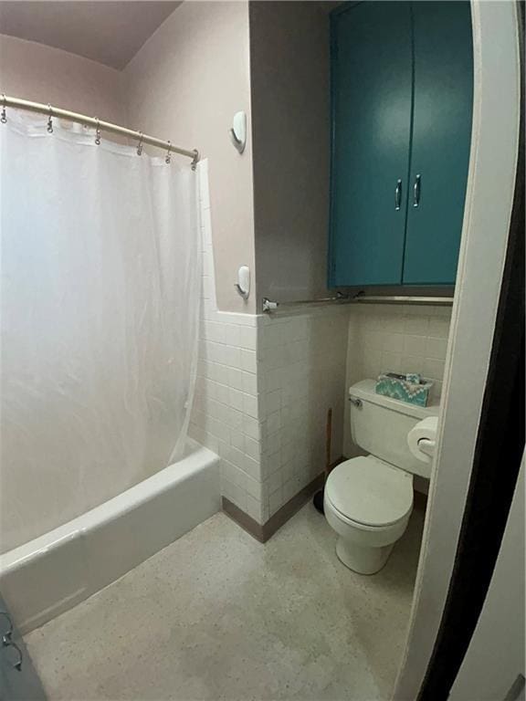 full bath featuring toilet, tile walls, a wainscoted wall, and shower / tub combo with curtain