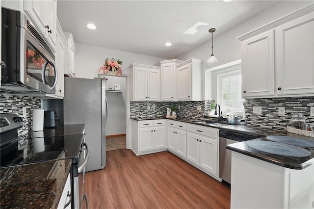 1605 NW Primrose Ln, Blue Springs, MO 64015 - kitchen featuring appliances with stainless steel finishes, wood finished floors, white cabinetry, decorative backsplash, and a textured ceiling