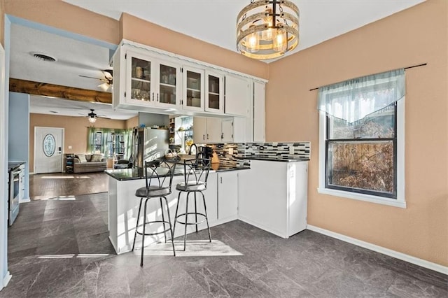 kitchen featuring dark countertops, a peninsula, healthy amount of natural light, and white cabinetry
