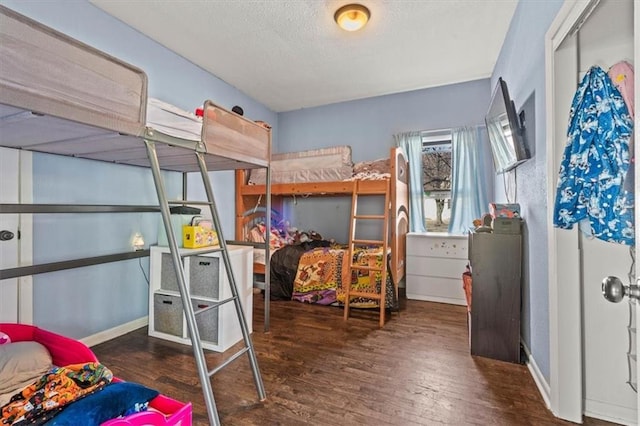 bedroom with wood finished floors, a textured ceiling, and baseboards