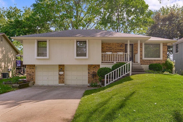 5004 S Kendall Dr, Independence, MO 64055 - view of front facade with an attached garage, brick siding, a front lawn, driveway, and covered porch