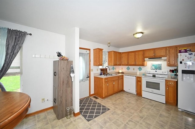 705 N Clark St, Edgerton, MO 64444 - kitchen with white appliances, under cabinet range hood, light countertops, a sink, and brown cabinetry