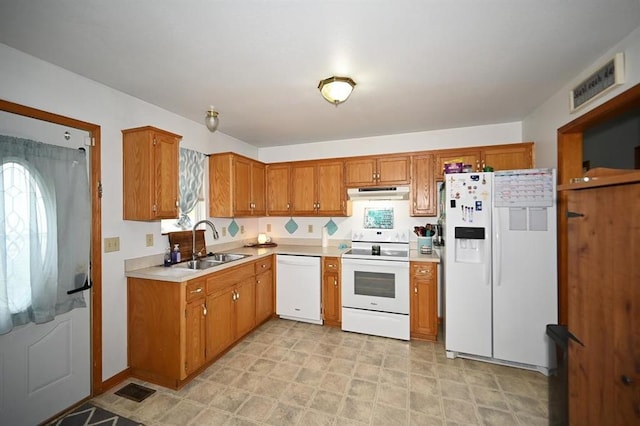 705 N Clark St, Edgerton, MO 64444 - kitchen featuring white appliances, under cabinet range hood, a sink, light countertops, and brown cabinetry
