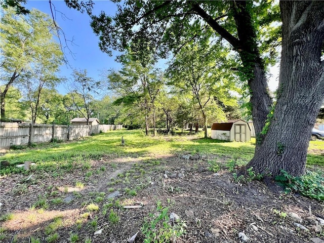 view of yard featuring a shed, fence, and an outdoor structure
