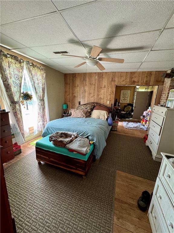 bedroom featuring wooden walls and a paneled ceiling