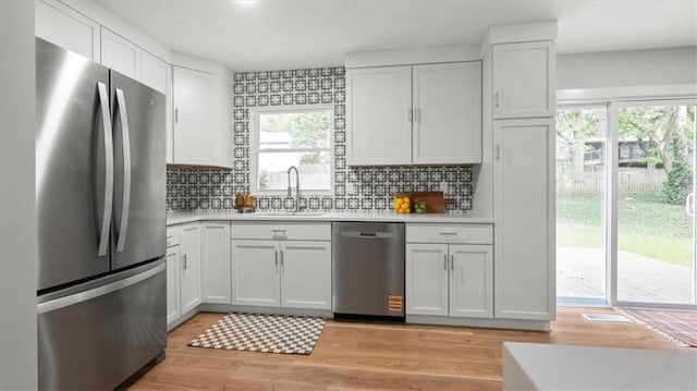 8741 Reeds Rd, Overland Park, KS 66207 - kitchen with appliances with stainless steel finishes, a sink, light countertops, white cabinetry, and light wood finished floors