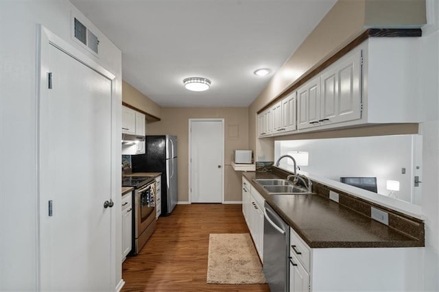 470 W 104th St Unit C, Kansas City, MO 64114 - kitchen featuring a sink, stainless steel appliances, dark countertops, and white cabinetry
