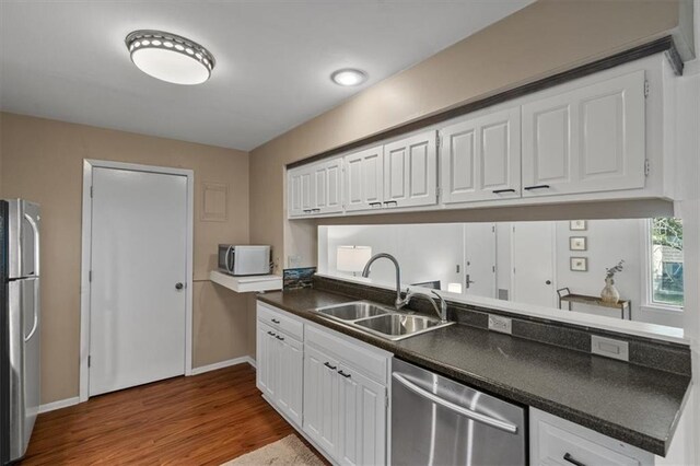470 W 104th St Unit C, Kansas City, MO 64114 - kitchen featuring appliances with stainless steel finishes, a sink, dark countertops, white cabinets, and dark wood-style flooring