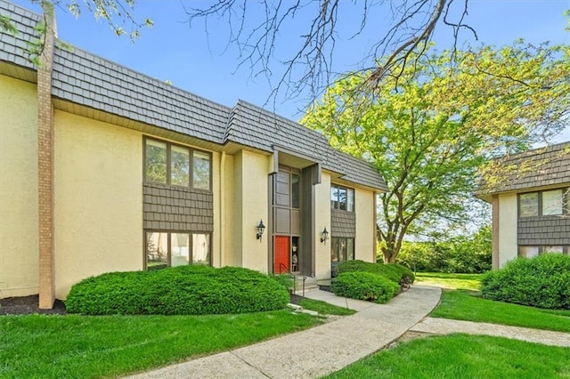 470 W 104th St Unit C, Kansas City, MO 64114 - view of exterior entry with mansard roof, stucco siding, and a lawn